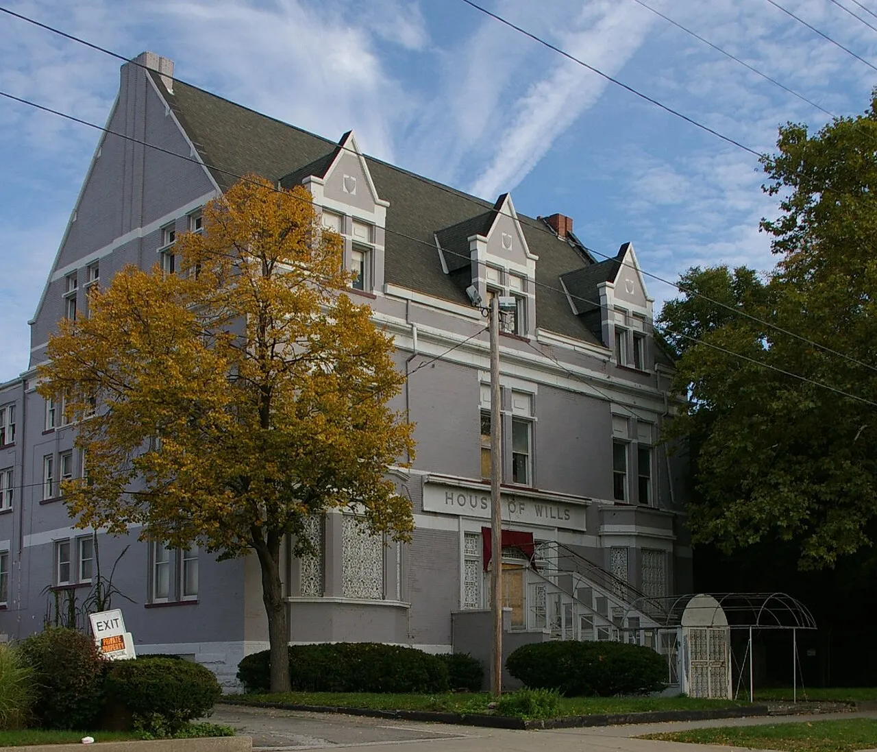 a large grey building with trees and a fence